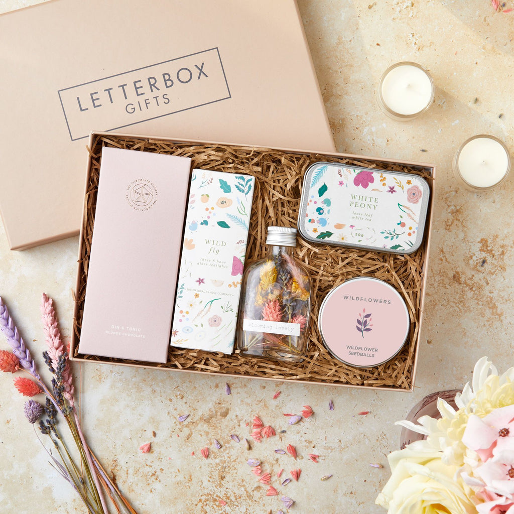 Letterbox gift set containing gin & tonic chocolate bar, wild fig tealights, white peony tea tin, wildflower seedballs and dried flowers in a glass bottle
