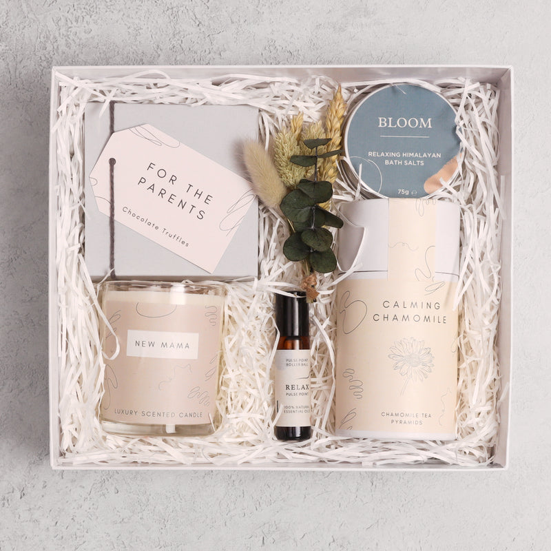 New Mum luxury gift hamper containing calming chamomile tea in cardboard tube, new mama candle, relax pulse point roll on, bloom bath soak, butterscotch truffles and natural dried flower sprig