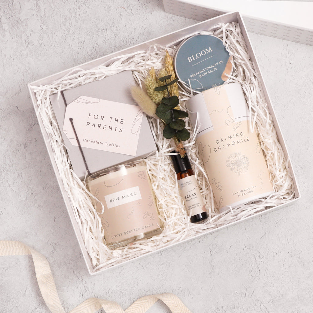 New Mum luxury gift hamper containing calming chamomile tea in cardboard tube, new mama candle, relax pulse point roll on, bloom bath soak, butterscotch truffles and natural dried flower sprig