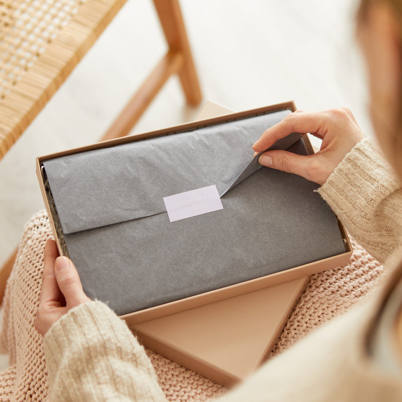 A person opening the grey tissue on their letterbox gift set