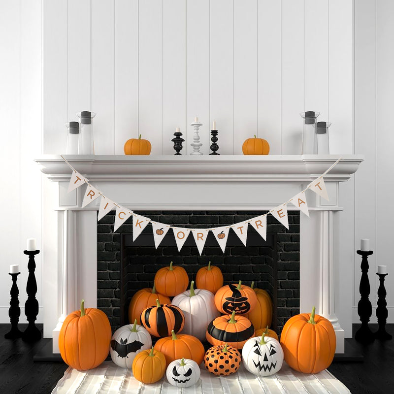 Trick or treat halloween bunting being displayed above a fireplace containing decorated pumplins