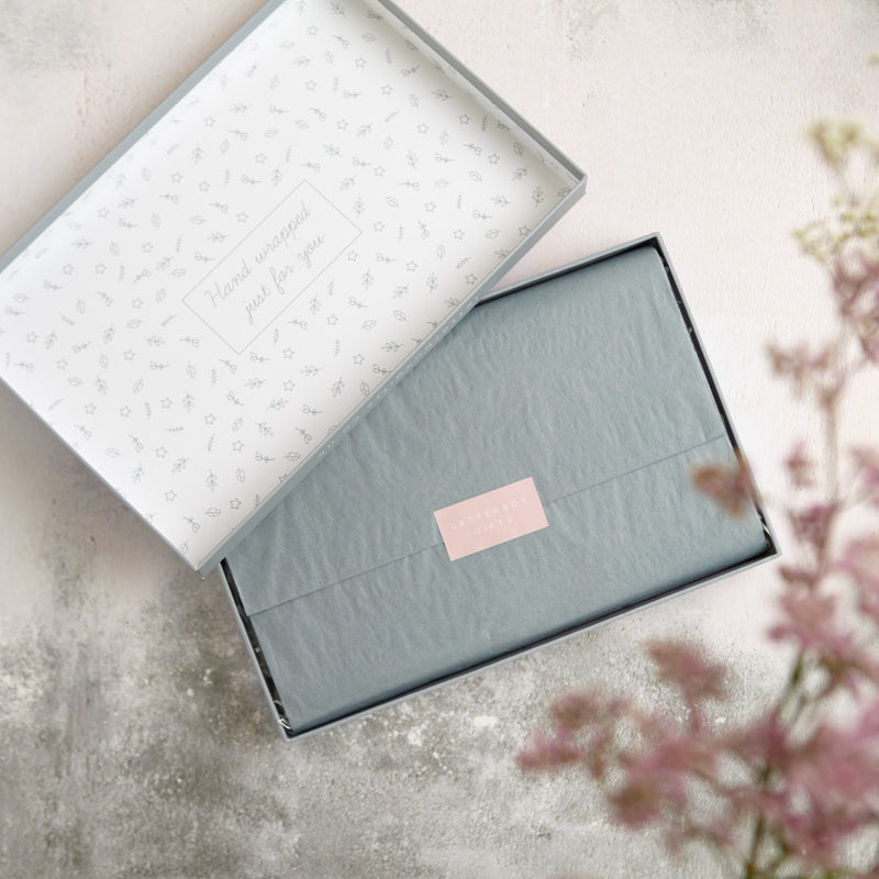 An open relaxation floral gift set showing the neatly wrapped grey tissue with pink Letterbox Gifts sticker