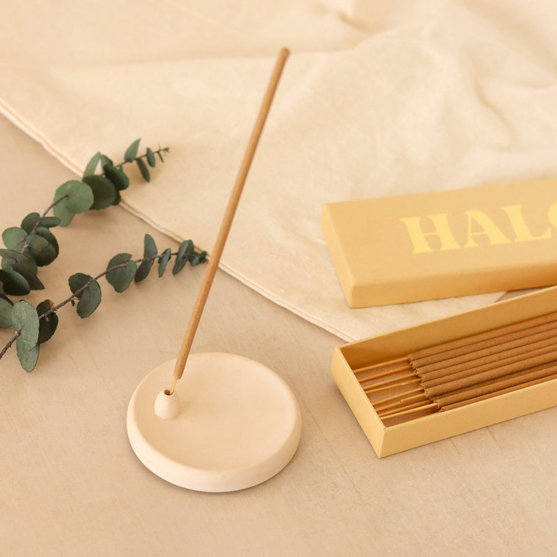 Nag Champal incense stick in a incense holder next to a yellow gift box containing fifteen incense sticks