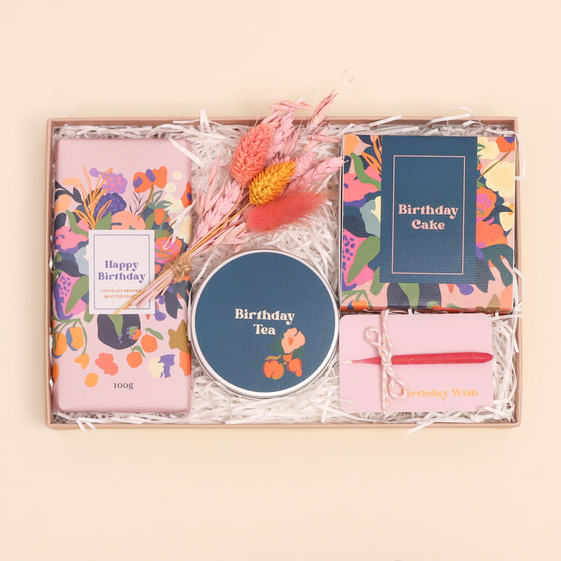 Birthday gift set containing chocolate brownie chocolate, darjeeling tea, birthday candle, birthday mug cake and dried flower posy, in pink and blue floral design