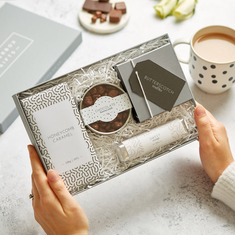 A person enjoying their monochrome chocolate gift set with a cup of tea