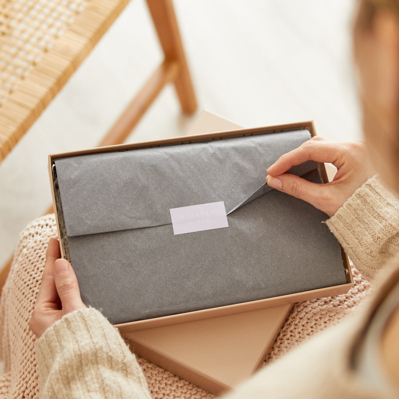 A person opening the grey tissue on their letterbox gift set