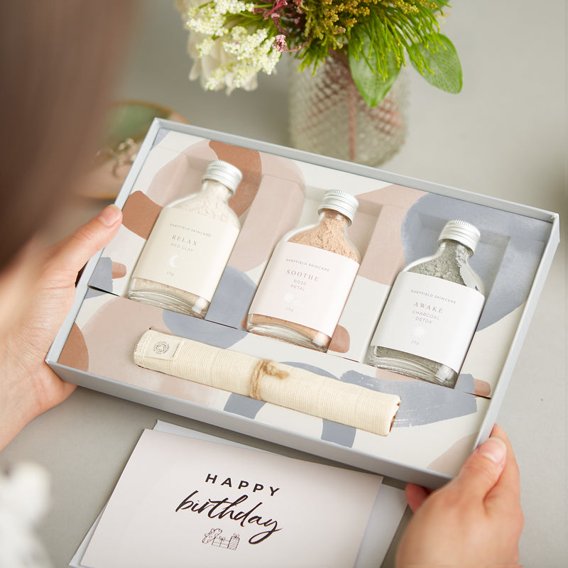 Facial spa gift set containing three clay face masks in glass bottles and muslin face cloth