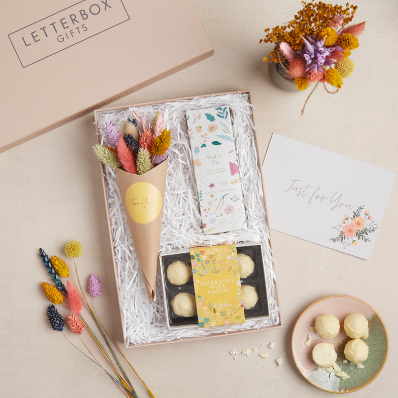 Celebration letterbox gift set containing sparkling wine chocolate truffles, wild fig tealights in botanical design & bright dried flower posy
