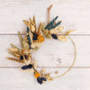Dried flower wreath constructed using blue, yellow, gold & natural dried flowers on a gold hoop
