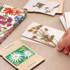 A person opening their wooden flower press gift set to reveal a pressed flower inside