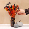 Orange, yellow and black halloween dried flower bouquet with black bat in brown glass jar