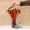 Orange, yellow and black halloween dried flower bouquet with black bat in brown glass jar