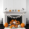 Trick or treat halloween bunting being displayed above a fireplace containing decorated pumplins