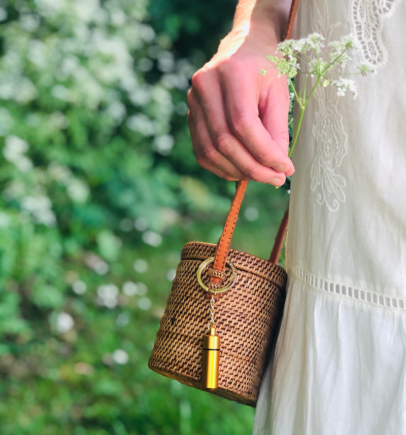 A lady in white dress with a bee revival kit keyring attached to her handbag
