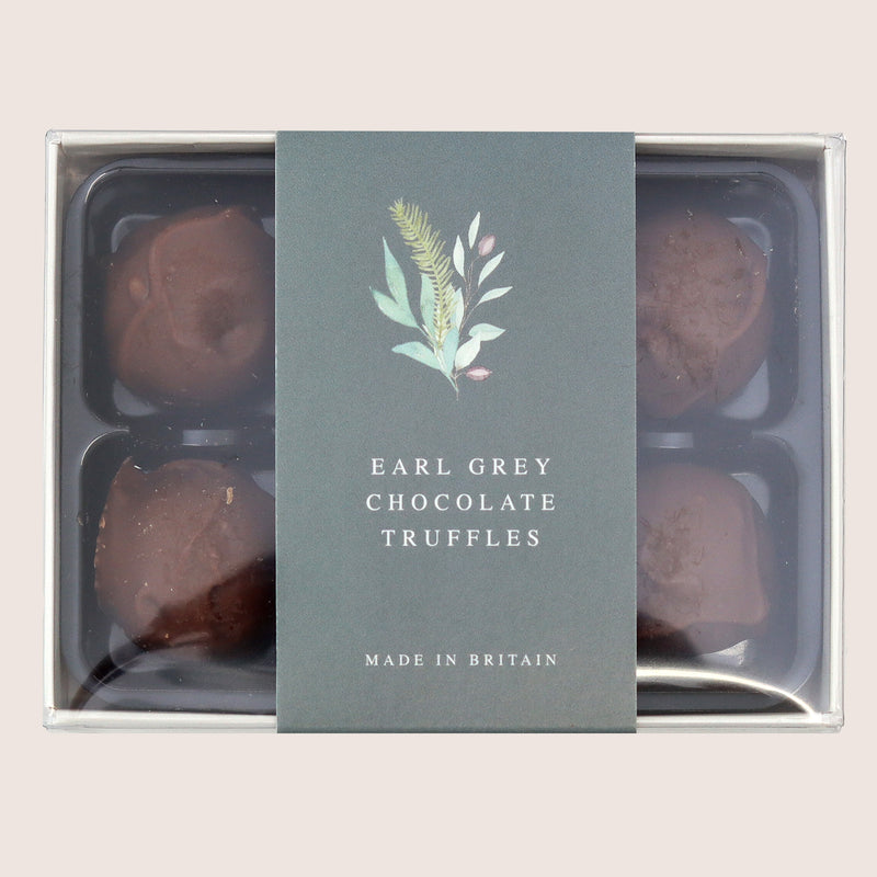 Six Earl grey chocolate truffles in packaging with green leafy band