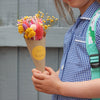 A child holding a bright summer thank you teacher dried flower posy in Kraft cone with 'Mrs Thompson' sticker