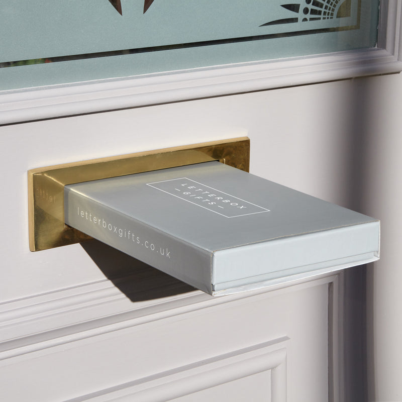 a grey letterbox gift box being posted through the letterbox of a grey door