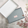 An open relaxation floral gift set showing the neatly wrapped grey tissue with pink Letterbox Gifts sticker