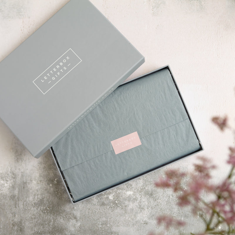 An open grey letterbox gift box showing the neatly wrapped interior with tissue and a letterbox gifts sticker