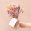 Mother's Day pink, purple, yellow and natural dried flower bouquet with 'for mum' swing tag, being displayed in a glass vase