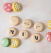 Fifteen hand-decorated colourful macarons with 'i love you mum' text and daisy flowers
