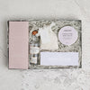 the 'Mums gin night in' Letterbox Gift showing the contents of a chocolate bar, a mini gin, a box of tealights and Himalayan bath salts, packaged in paper straw