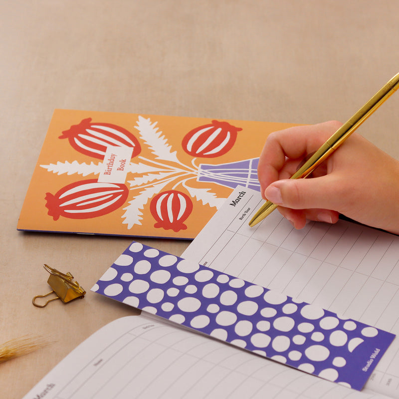 A person writing in their purple address book 