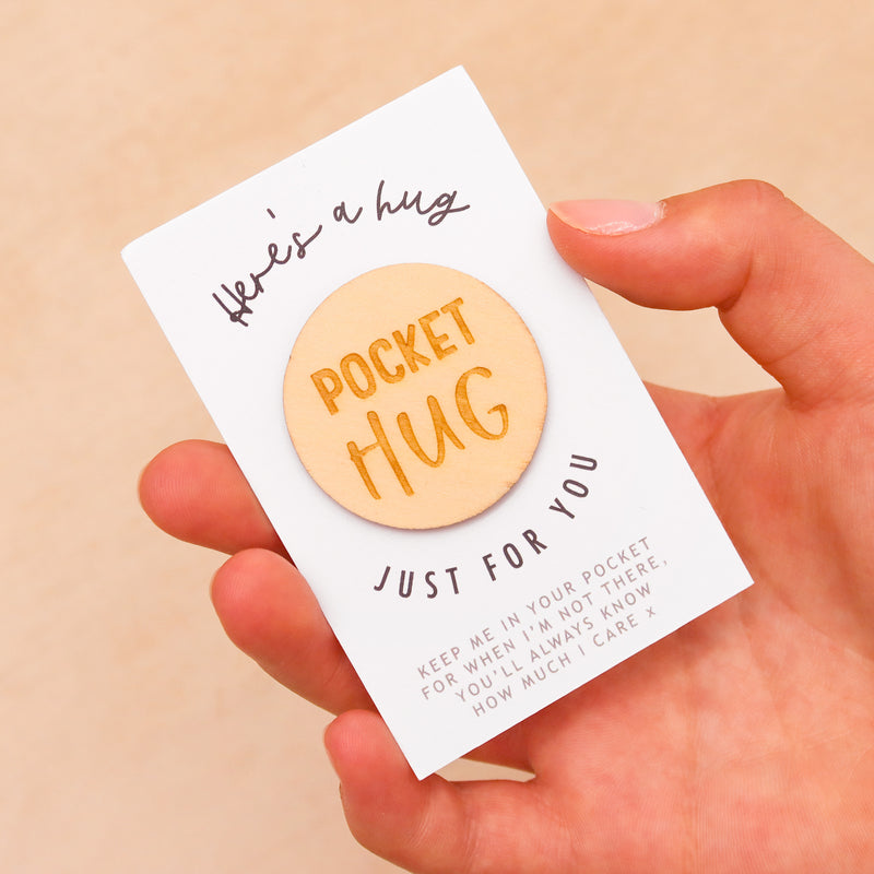 Wooden circular token with the words 'pocket hug'