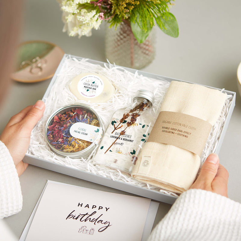 Eco friendly spa gift set containing organic cotton face cloth, bath essence, floral facial steam tin and cocoa butter massage bar