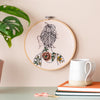 Round embroidery with a woman with tattooed shoulders hanging on a wall