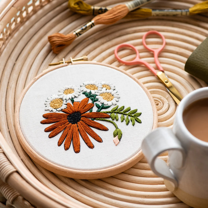 Round retro daisies embroidery set on a coffee table