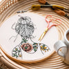 Round embroidery with a woman with tattooed shoulders 