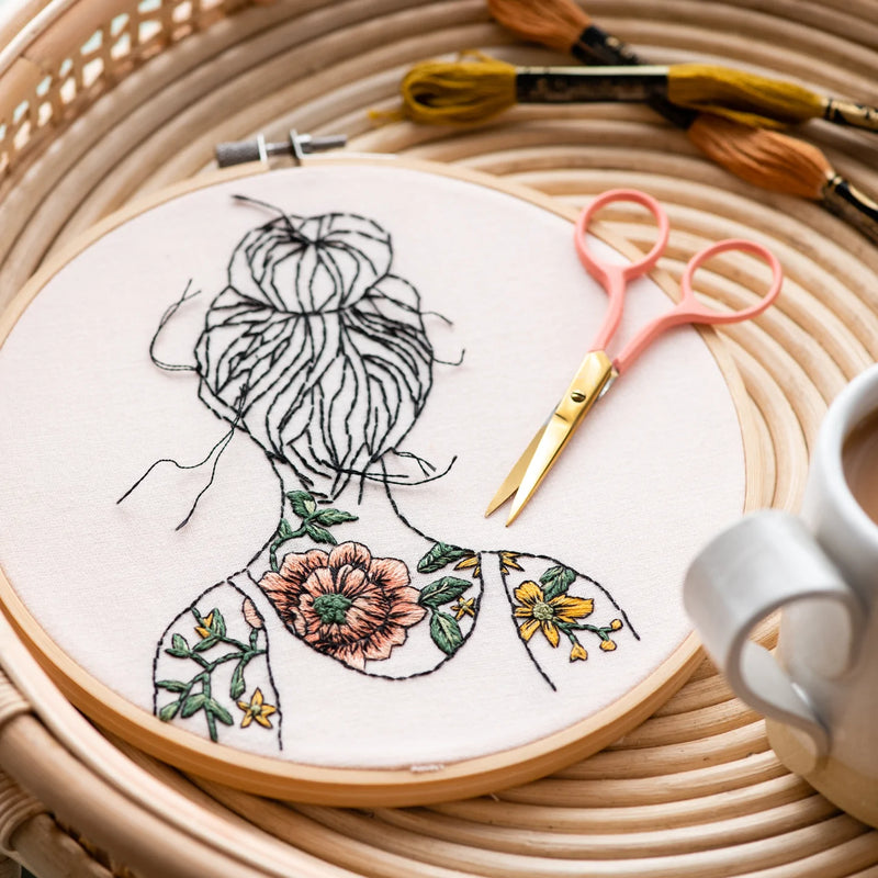 Round embroidery with a woman with tattooed shoulders 