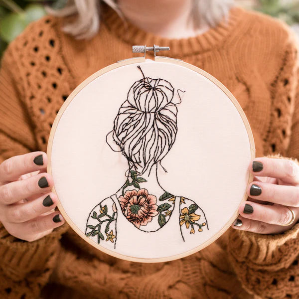 Round embroidery with a woman with tattooed shoulders