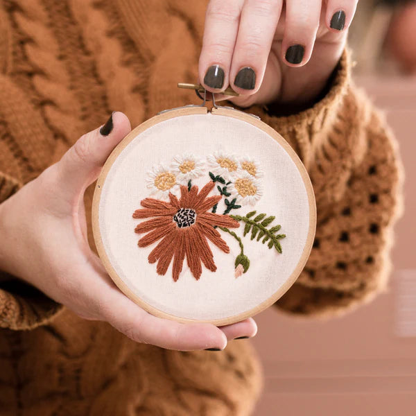 A person holding a round embroidery kit with retro daisies image