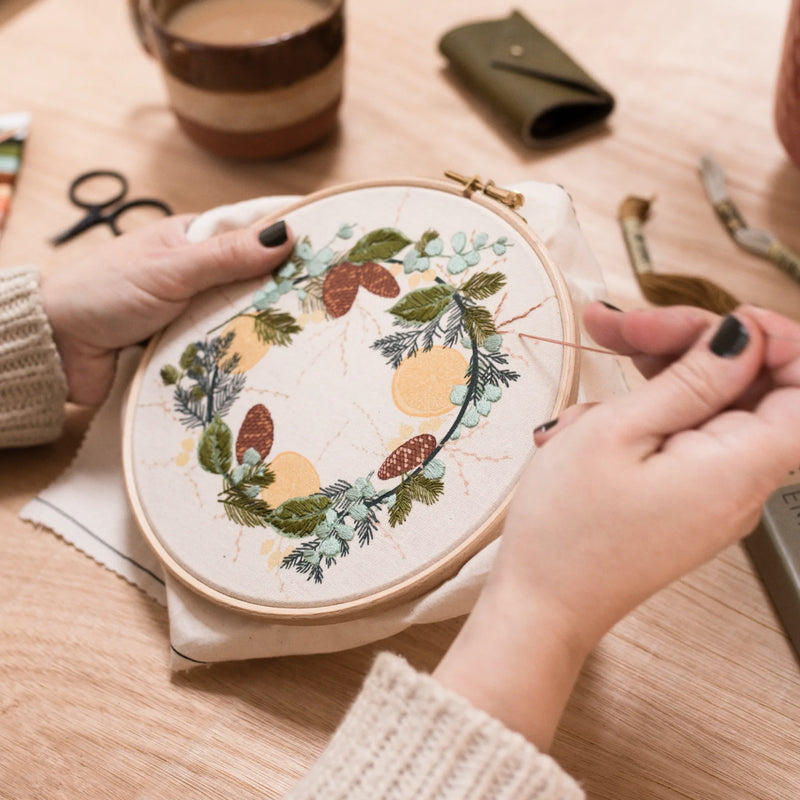 A person embroiding a wild wreath design