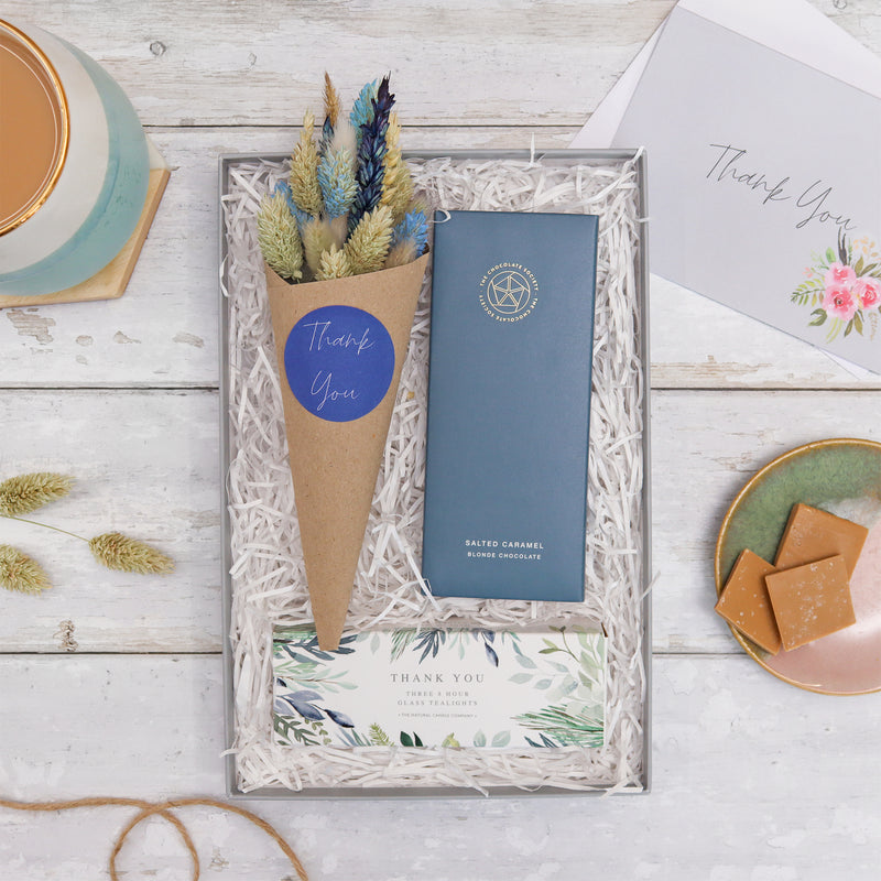 Thank You floral gift set containing a bar of chocolate in dark blue card packaging, a box of tealights with a green plant pattern with the words 'thank you', and a bouquet of dried flowers