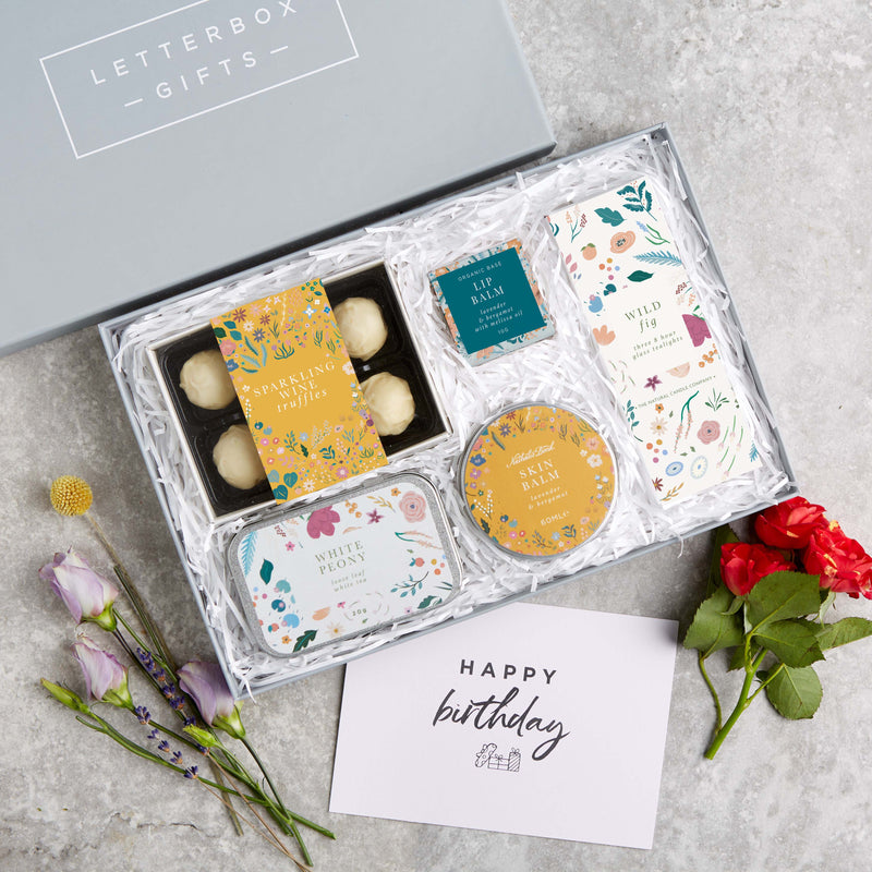 Botanical letterbox gift set containing sparkling wine truffles, lip balm, wild fig tealights, white peony tea & skin balm in bright floral design