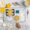 Botanical letterbox gift set containing sparkling wine truffles, lip balm, wild fig tealights, white peony tea & skin balm in bright floral design