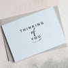 a light blue A6 grettings cards with the words 'thinking of you' in a clear black font