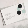 A6 pale pink greetings card with happy birthday text and black and green balloons