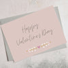 Pastel pink greetings card with 'happy valentine's day' text