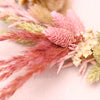 Close-up of pastel pink and white dried flowers arranged on a gold wreath hoop