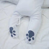 A baby in white polar bear baby grow showing the paw prints on the feet