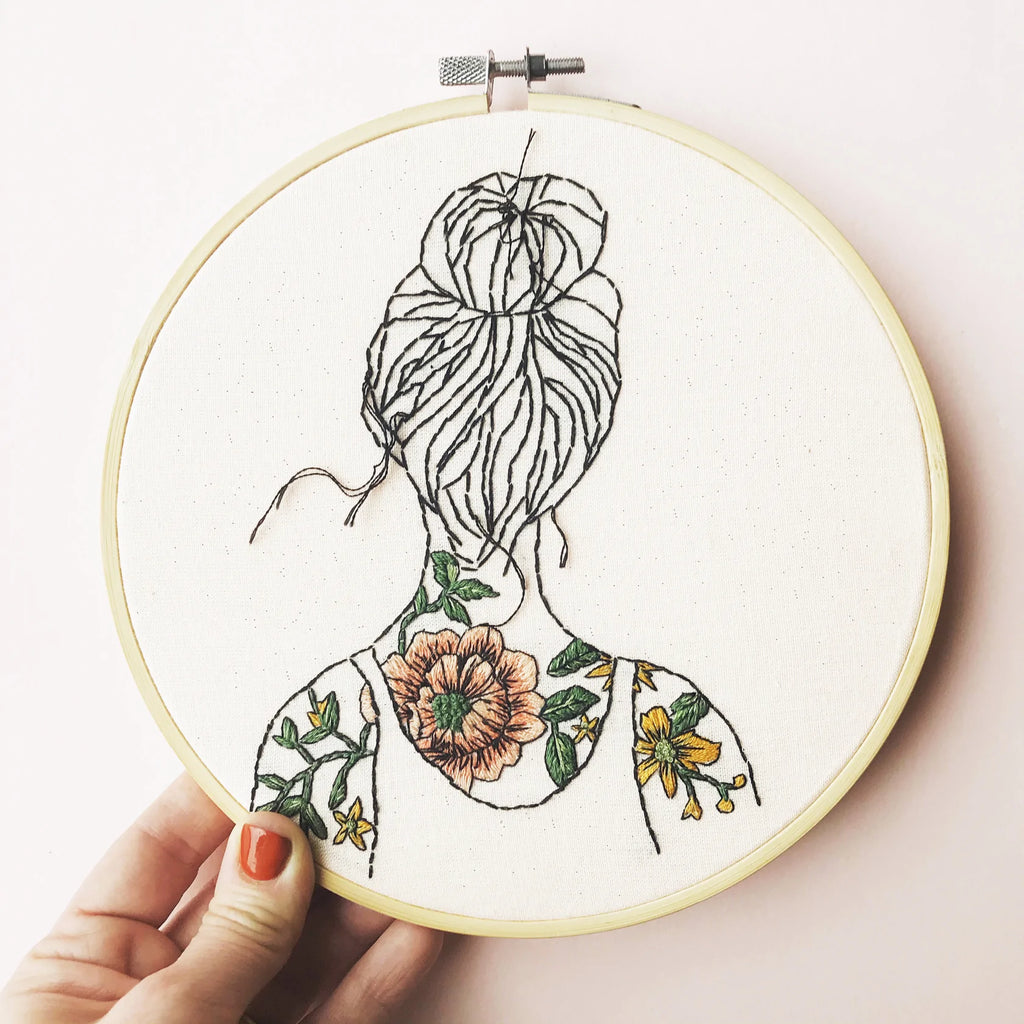 Round embroidery with a woman with tattooed shoulders