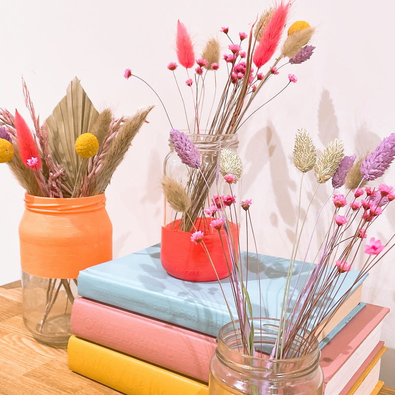 Dried flowers spring bouquet arranged in three colourful glass jars